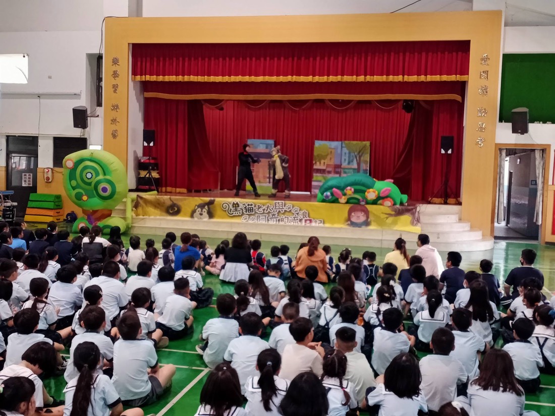 全校學生席地觀賞動物保護主題舞台劇 · The whole school watches the animal-protection stage play