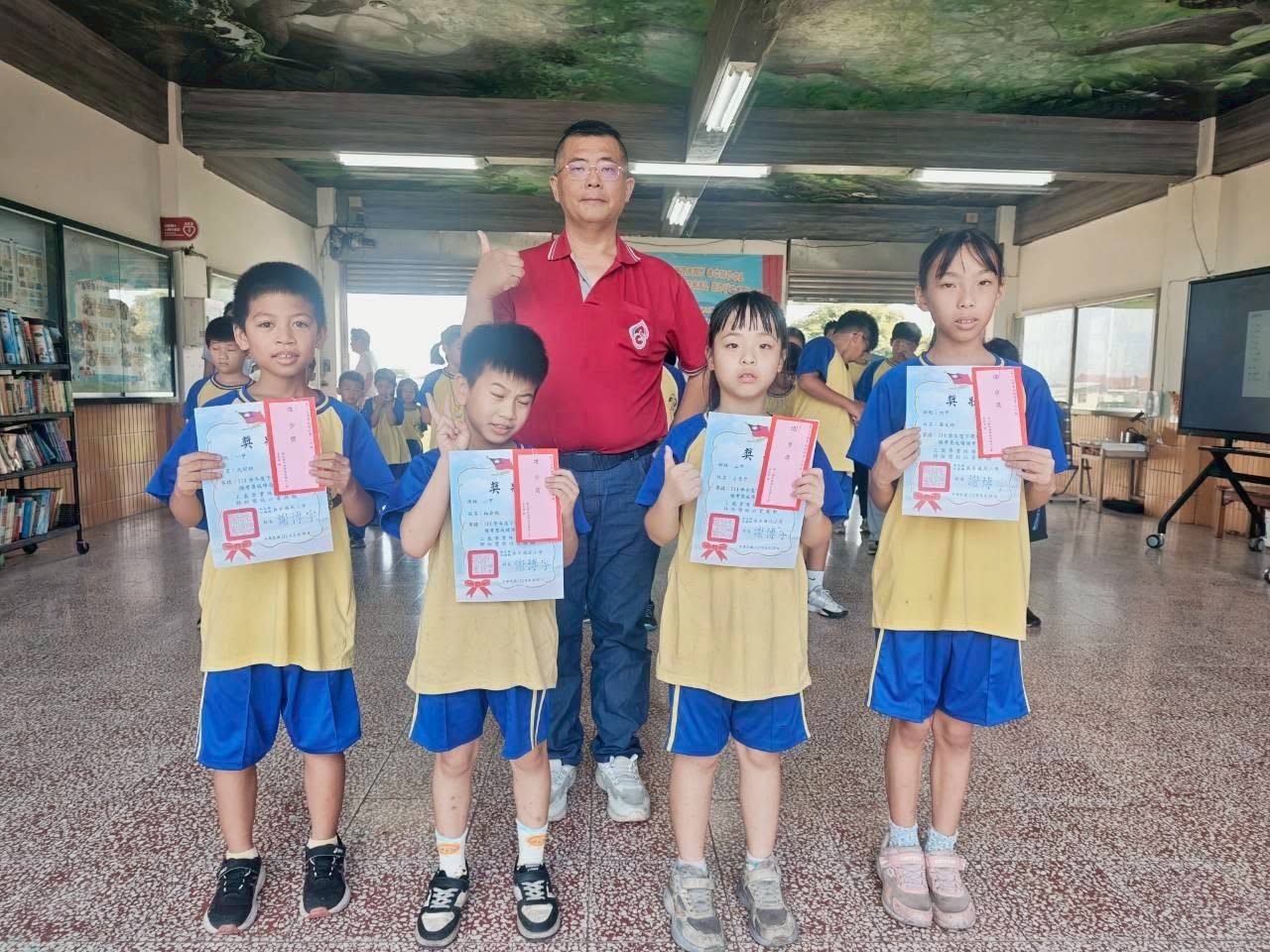 More students holding certificates with the principal at the closing ceremony