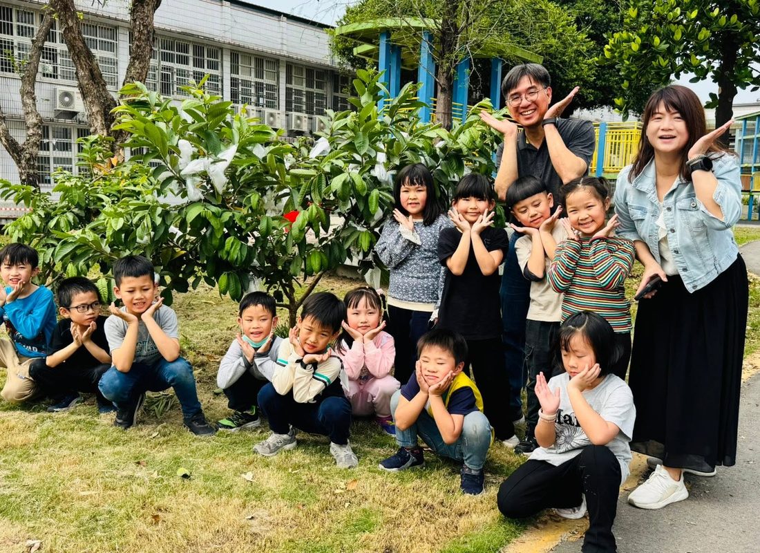 郭書源校長與朝興國小學生、老師在校園芭樂樹前合影