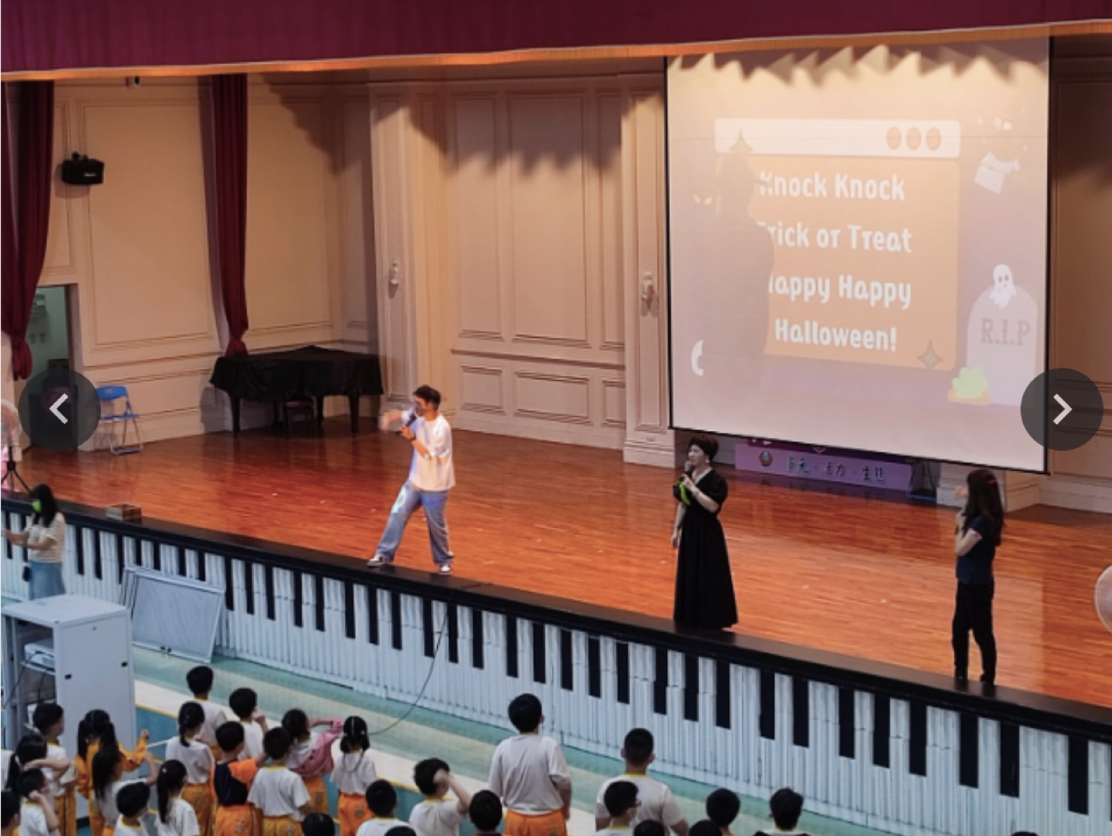 老師在舞台上帶領學生唱萬聖節英語歌曲Trick or Treat