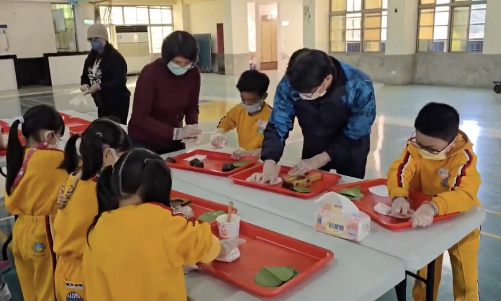 老師與學生一起在托盤上製作紅龜粿