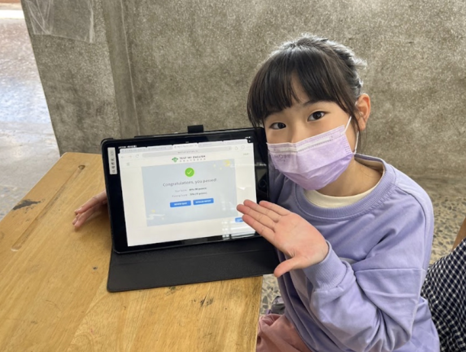 學生開心展示平板上英語自我檢測系統通過畫面