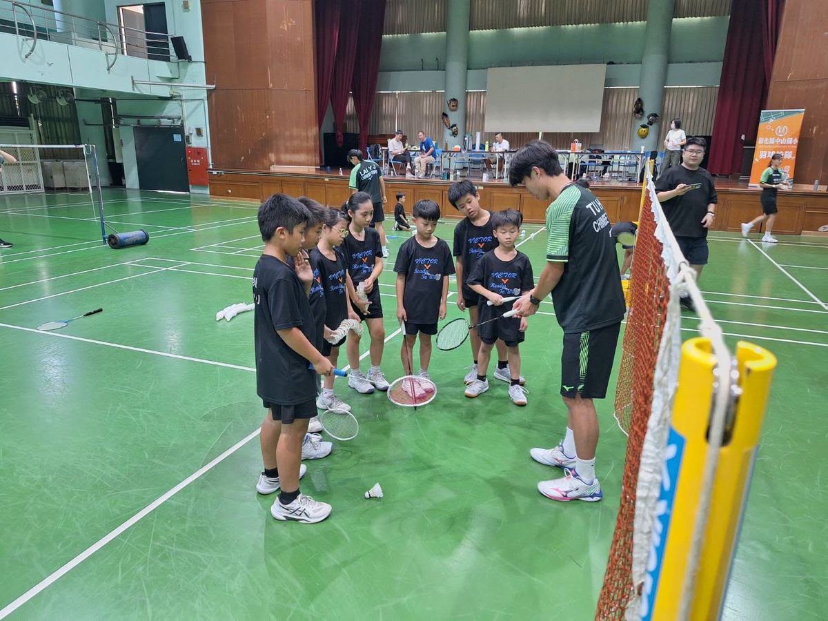 中租球員在網前指導孩子握拍姿勢