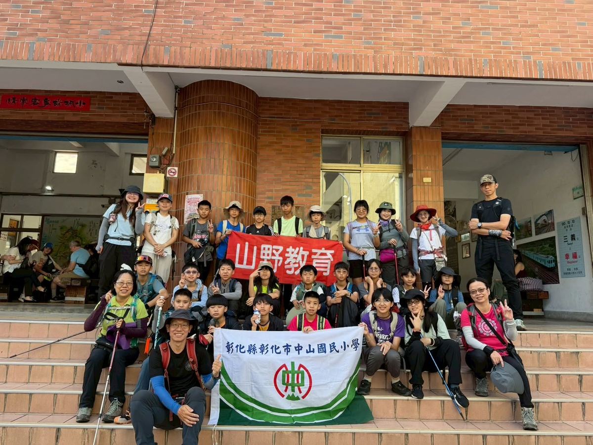 中山國小師生在三義車站前手持山野教育與校旗合影