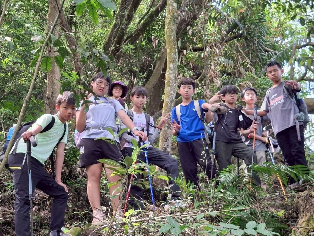 孩子們在森林步道中手持登山杖休息合影