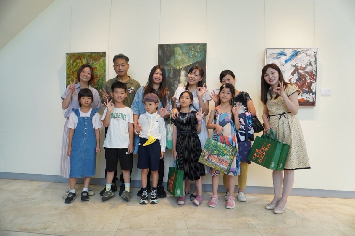 孩子們與家長、老師在展場合影，手提紀念禮袋