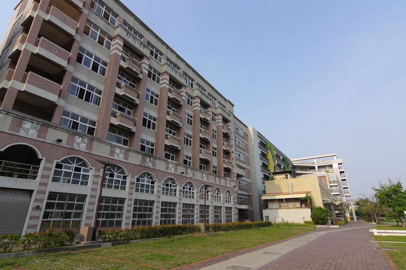 崇實高工紅磚立面的科館，一側是拱窗長廊與紅磚步道 A red-brick department building at ChungShih, its arched windows running the length of the façade beside a brick walkway