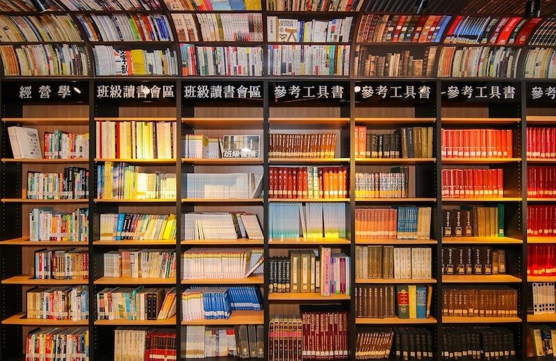 整面書架上依分類排滿書籍，標示著班級讀書會區與參考工具書 A full wall of shelves sorted by category, labelled for the class reading-group area and reference works