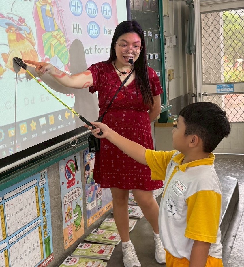 Teacher Mae teaching English at the smartboard with a Cundong student