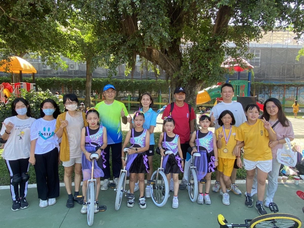 Cundong Unicycle Squad with teachers and parents under campus trees