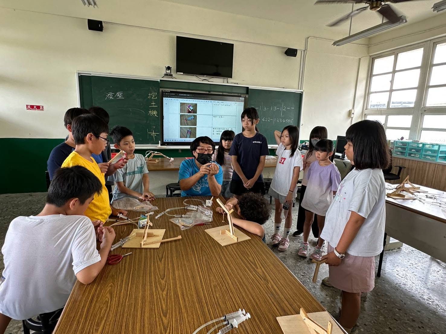 大園國小學生圍著老師學習液壓挖土機原理