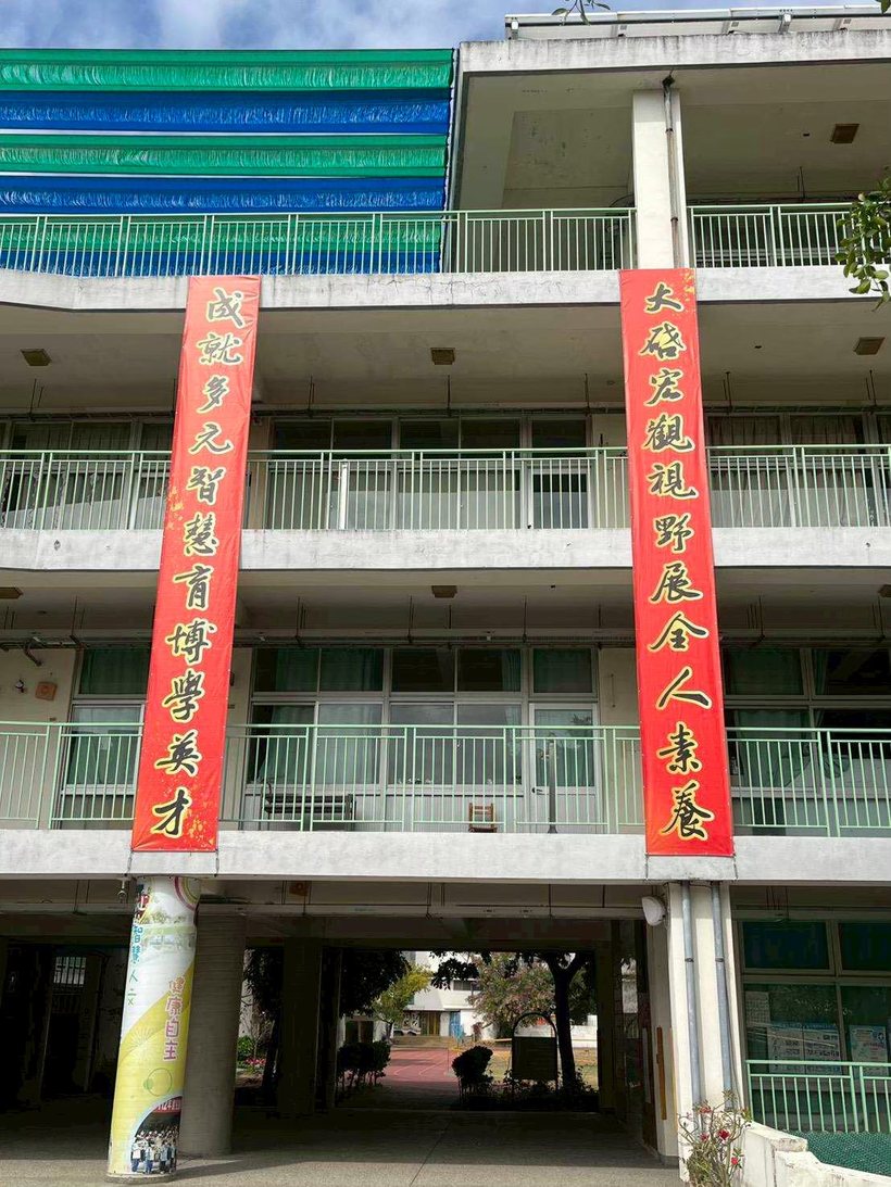 Two red banners on the teaching block, each opening with one character of the school's name
