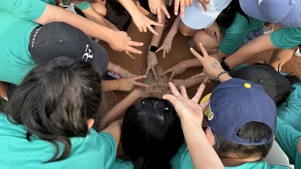 A class reaching their hands into a circle together, seen from above