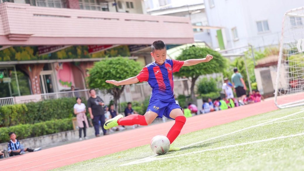 A Dacheng footballer striking the ball on the school pitch