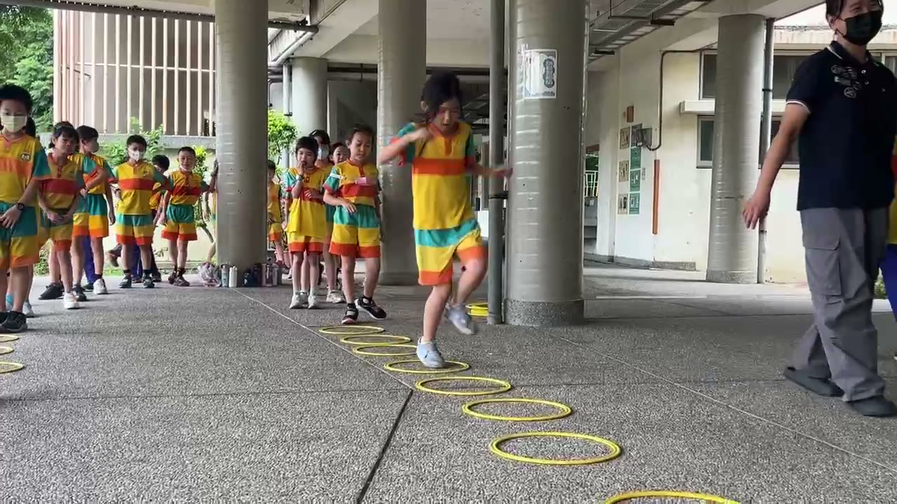 Students jumping along a line of yellow hoops in the breezeway