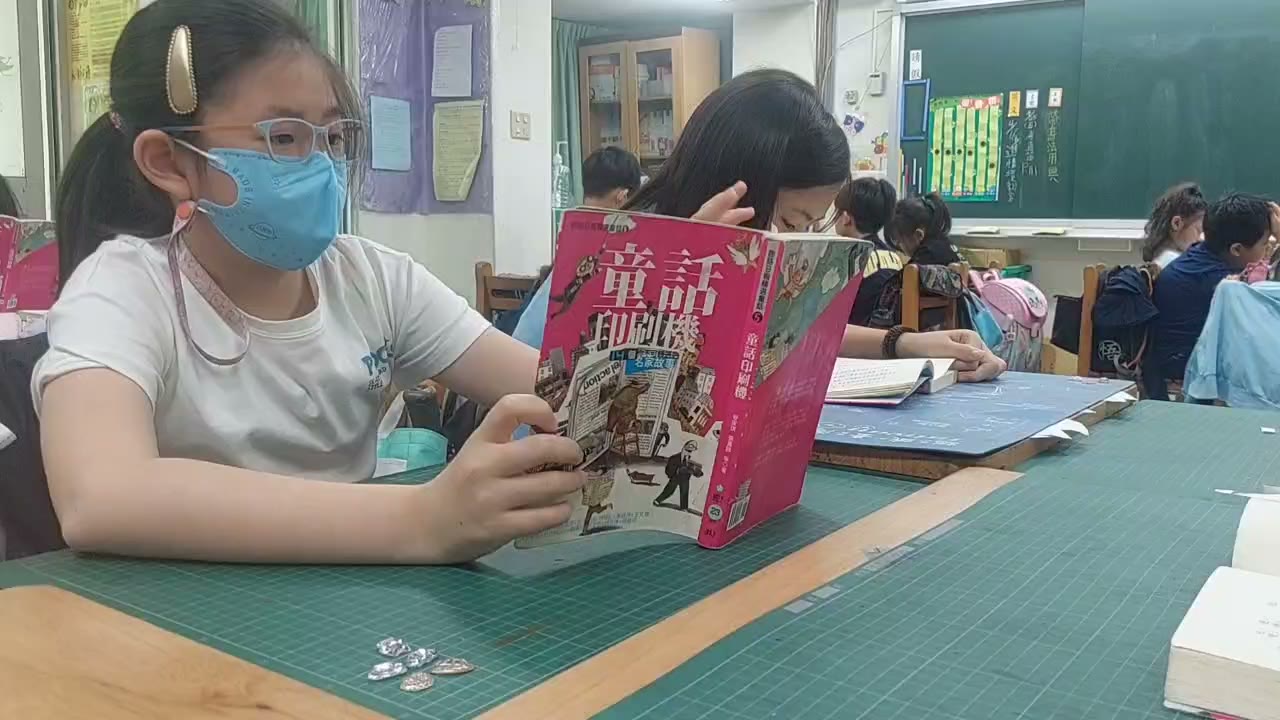 A student holding up the shared class reader at Dacheng