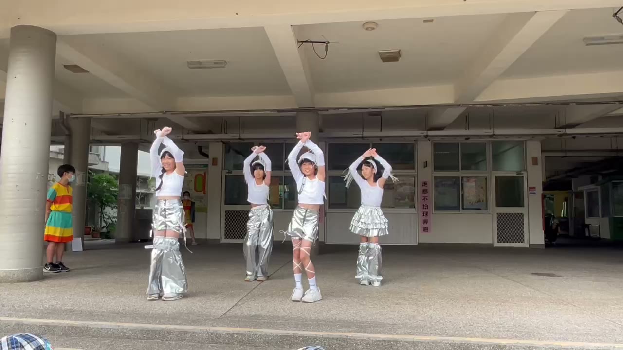 Four dancers in silver costumes perform in the breezeway