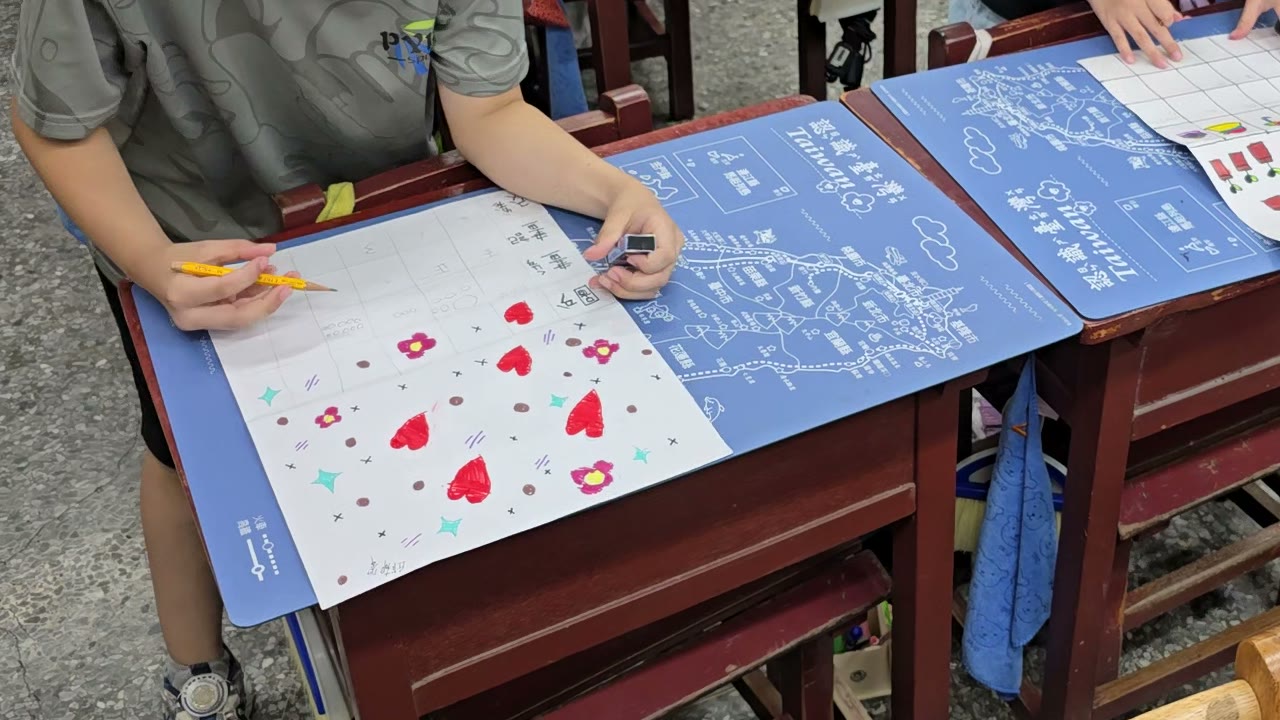A first grader draws hearts, flowers, and stars on a worksheet