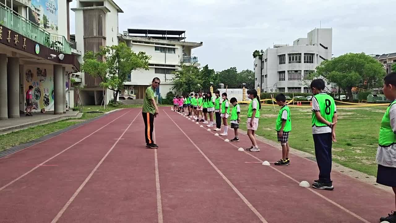 Fifth graders in green vests help count jumps on the track