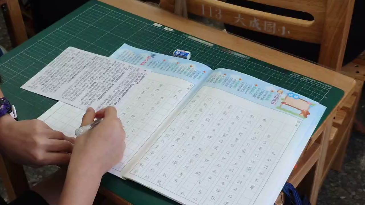 A student writing a composition in a grid notebook