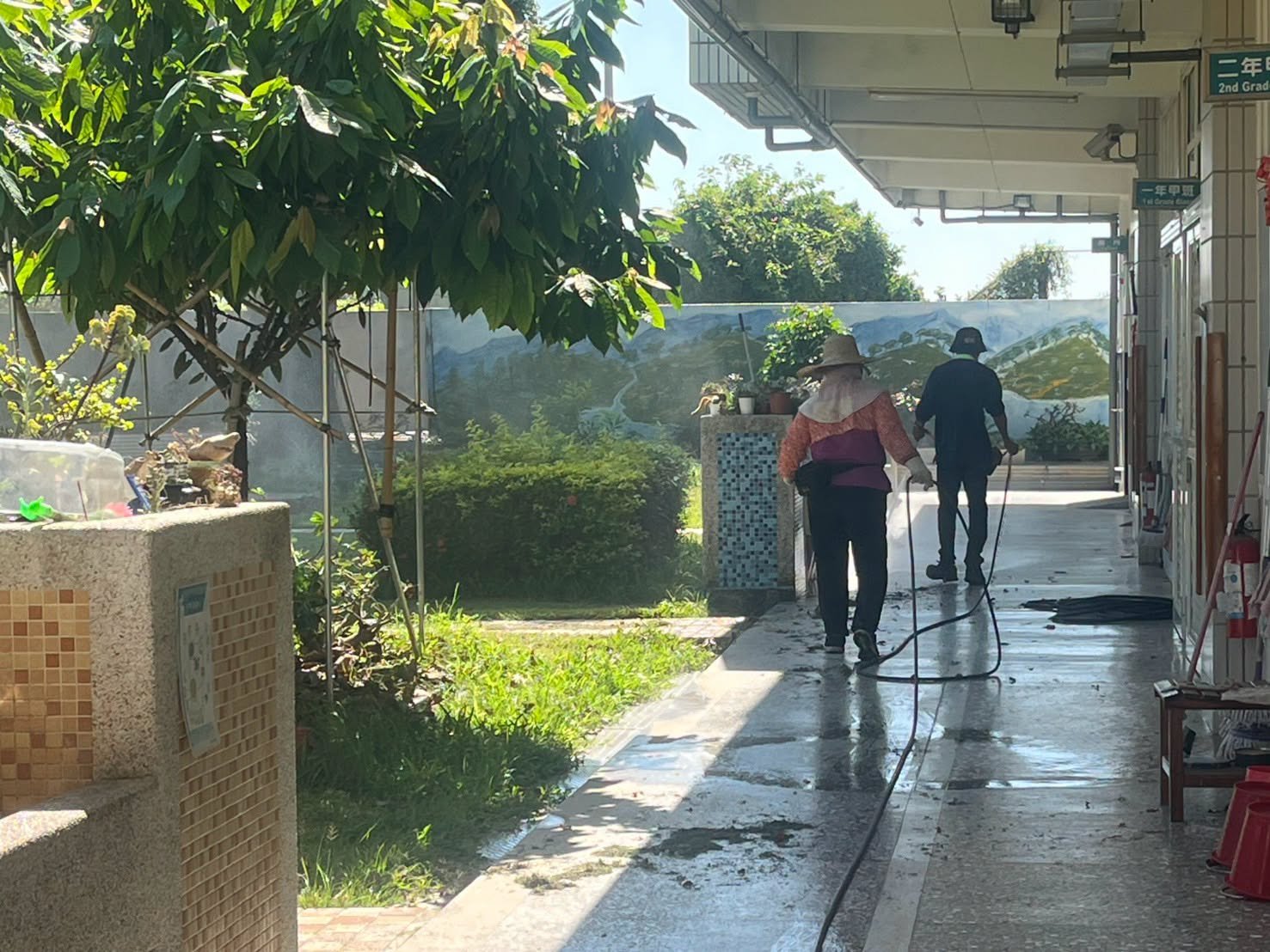 Workers spraying a covered walkway near the classrooms