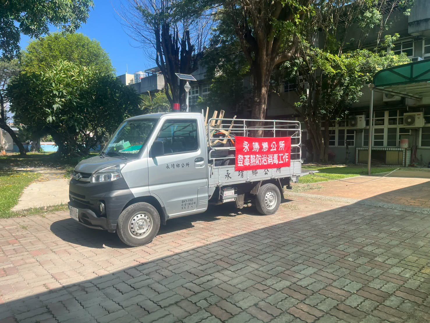 A Yongjing Township Office truck with a dengue-prevention banner parked on campus
