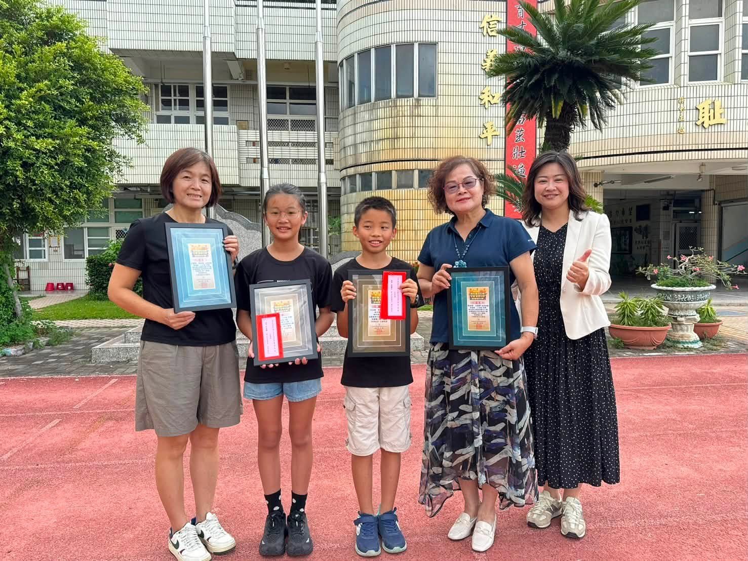 Desing students and teachers holding awards outside the school entrance