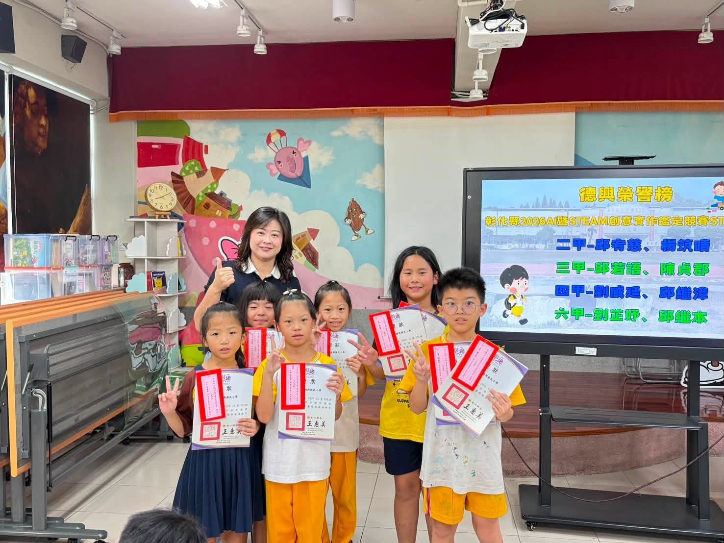 Students holding STEAM competition certificates in the library