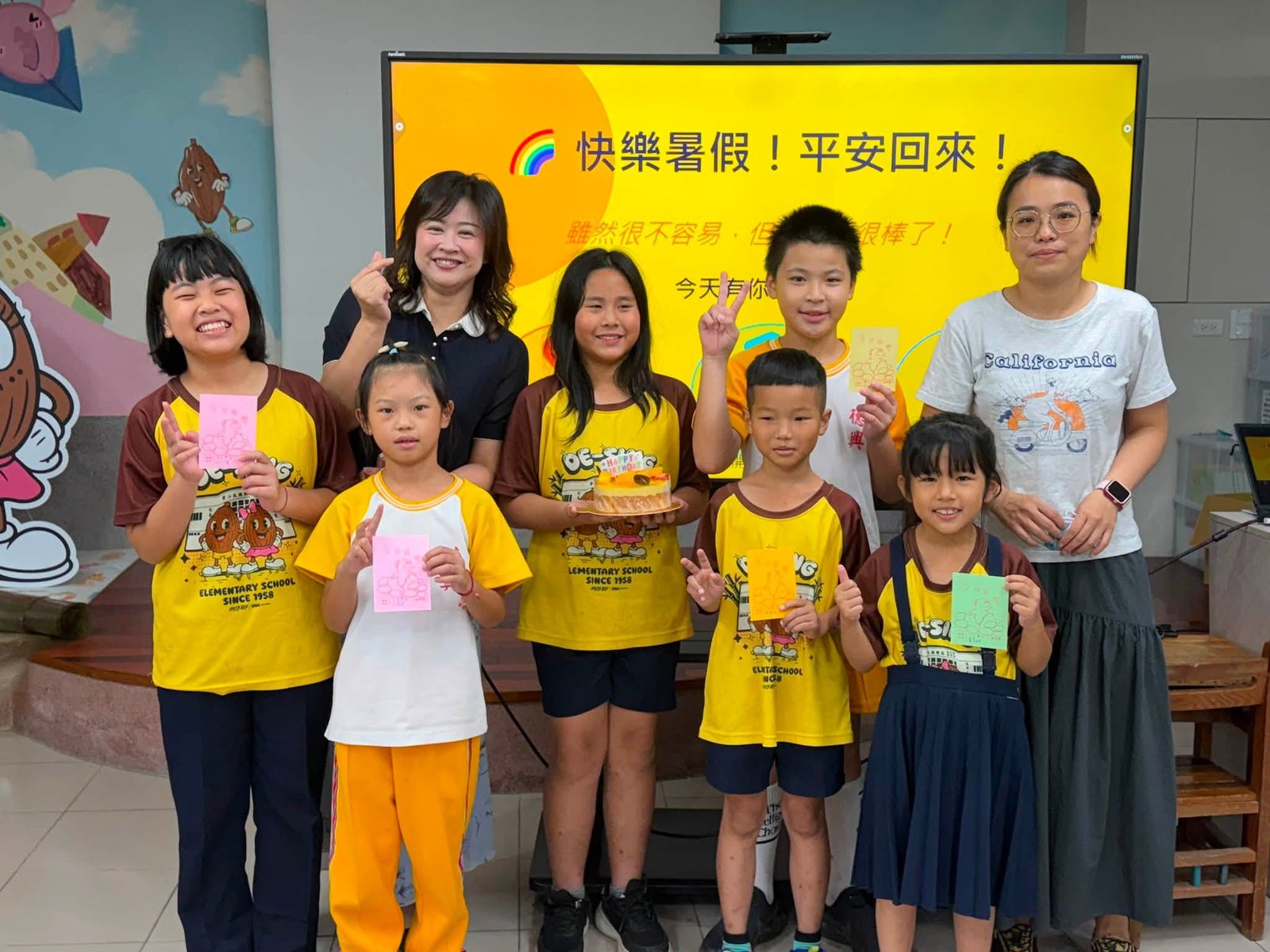 Students celebrating summer birthdays with a cake