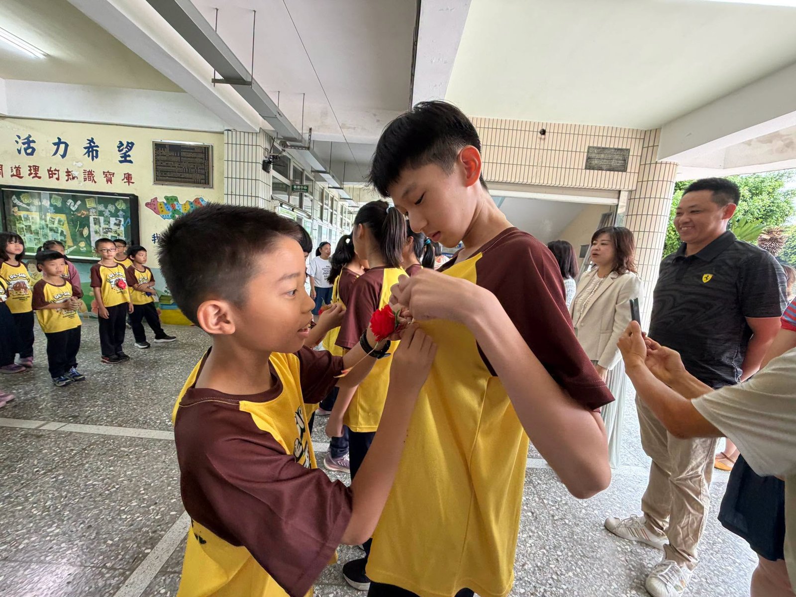 A graduate pinning a flower on a classmate in the hallway