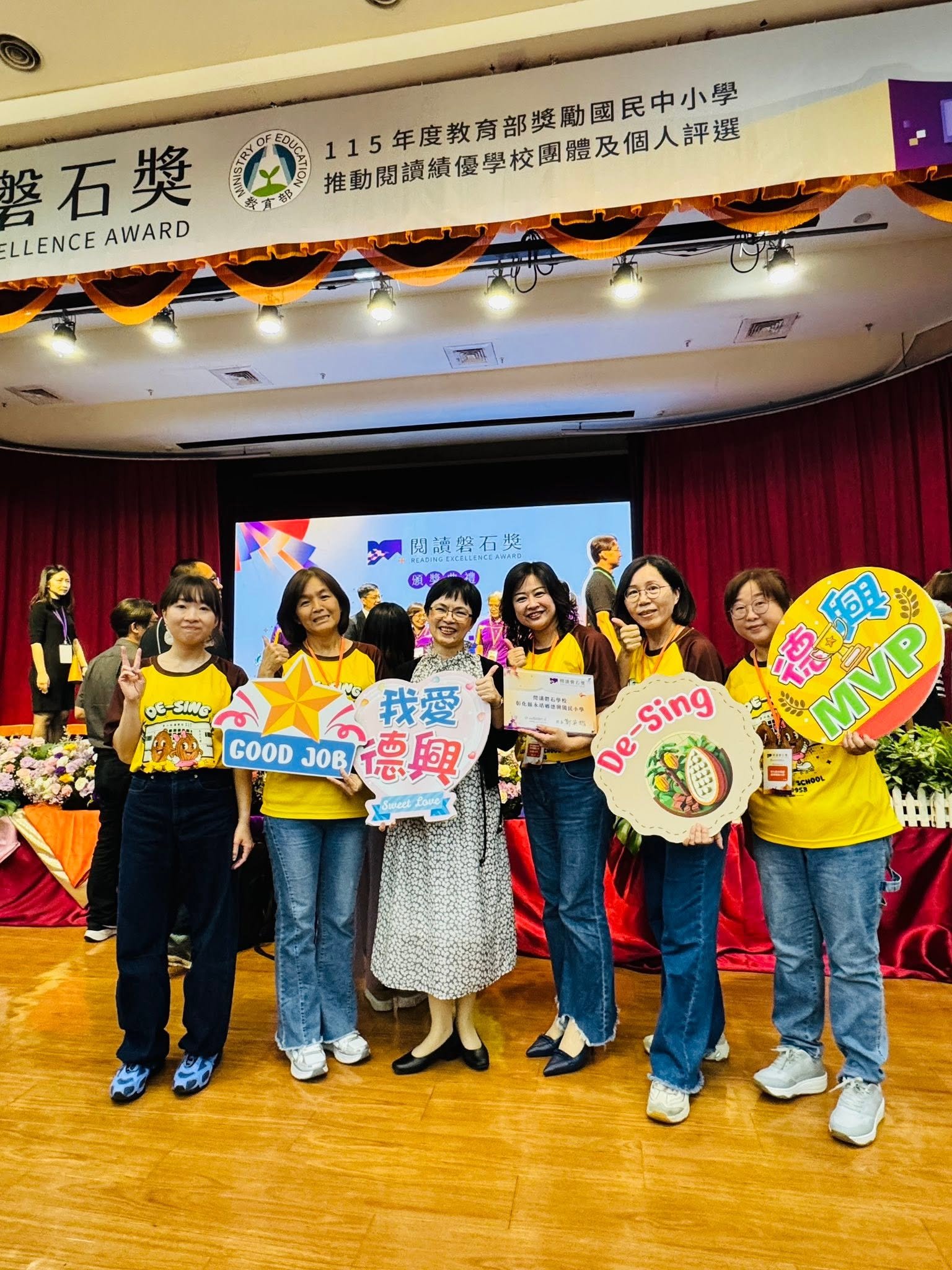 Desing teachers celebrating on stage in front of the Ministry of Education Reading Rock Award banner