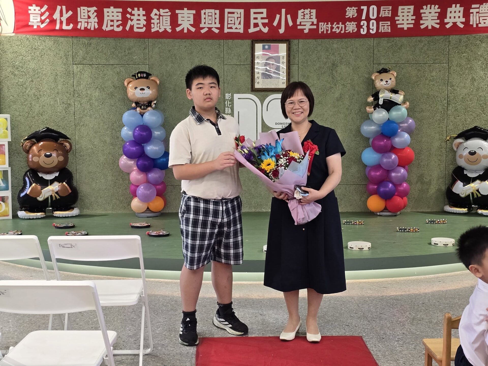 Principal Lin Ya-Hui presenting a bouquet to a graduating student