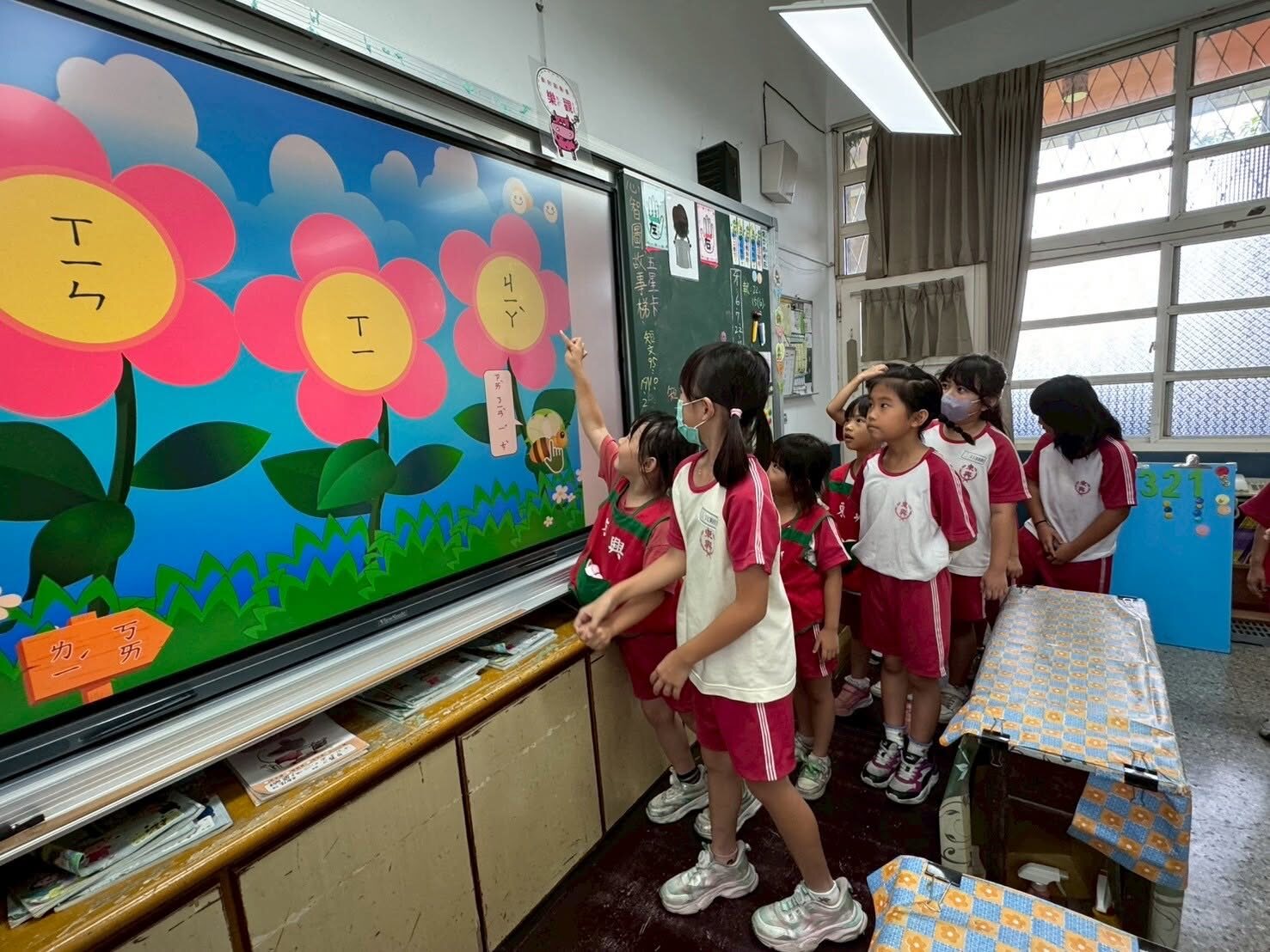 Kindergarteners following along on the interactive whiteboard during a phonics lesson