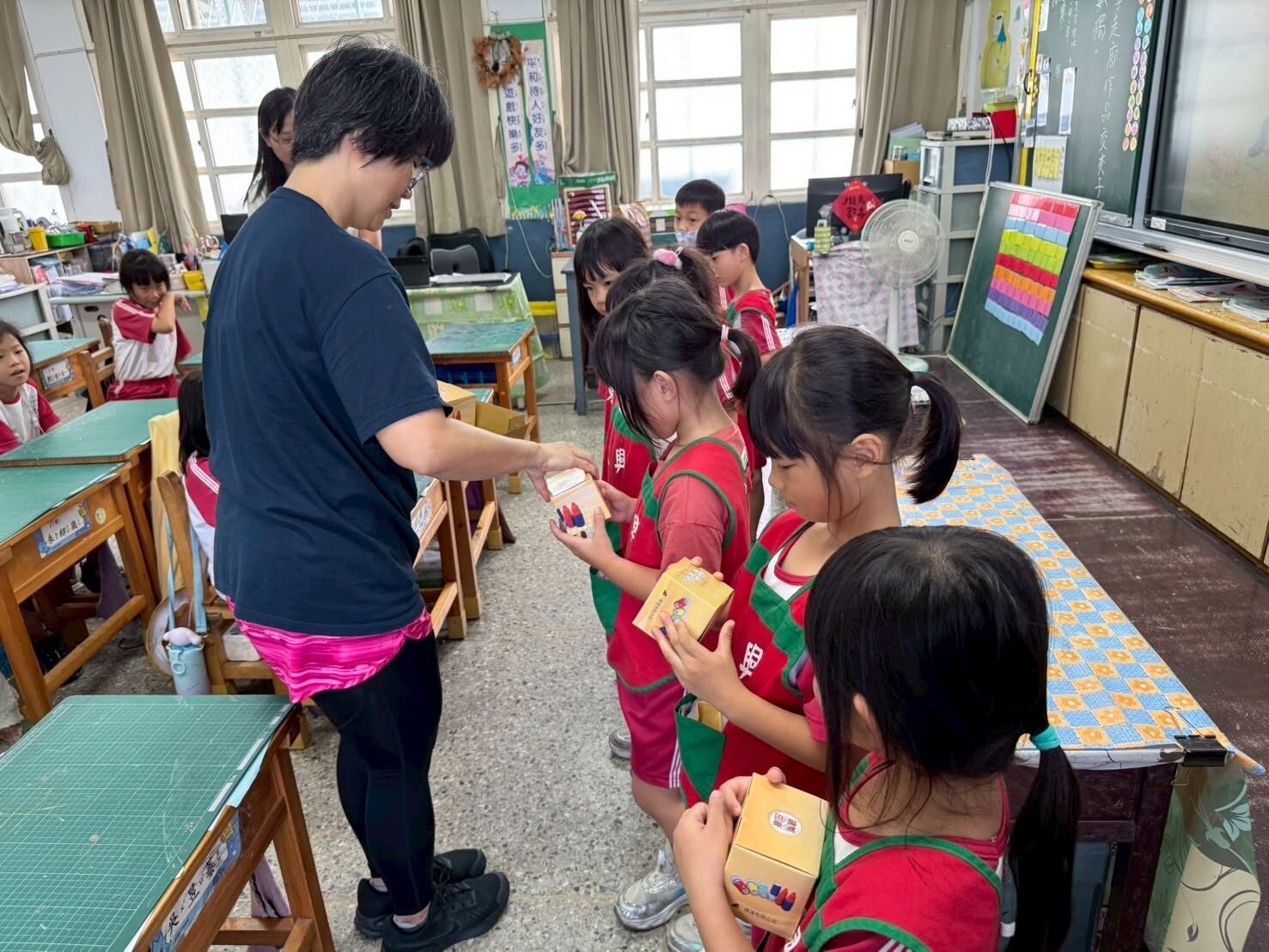 A teacher giving small gifts to Penguin Class kindergarteners