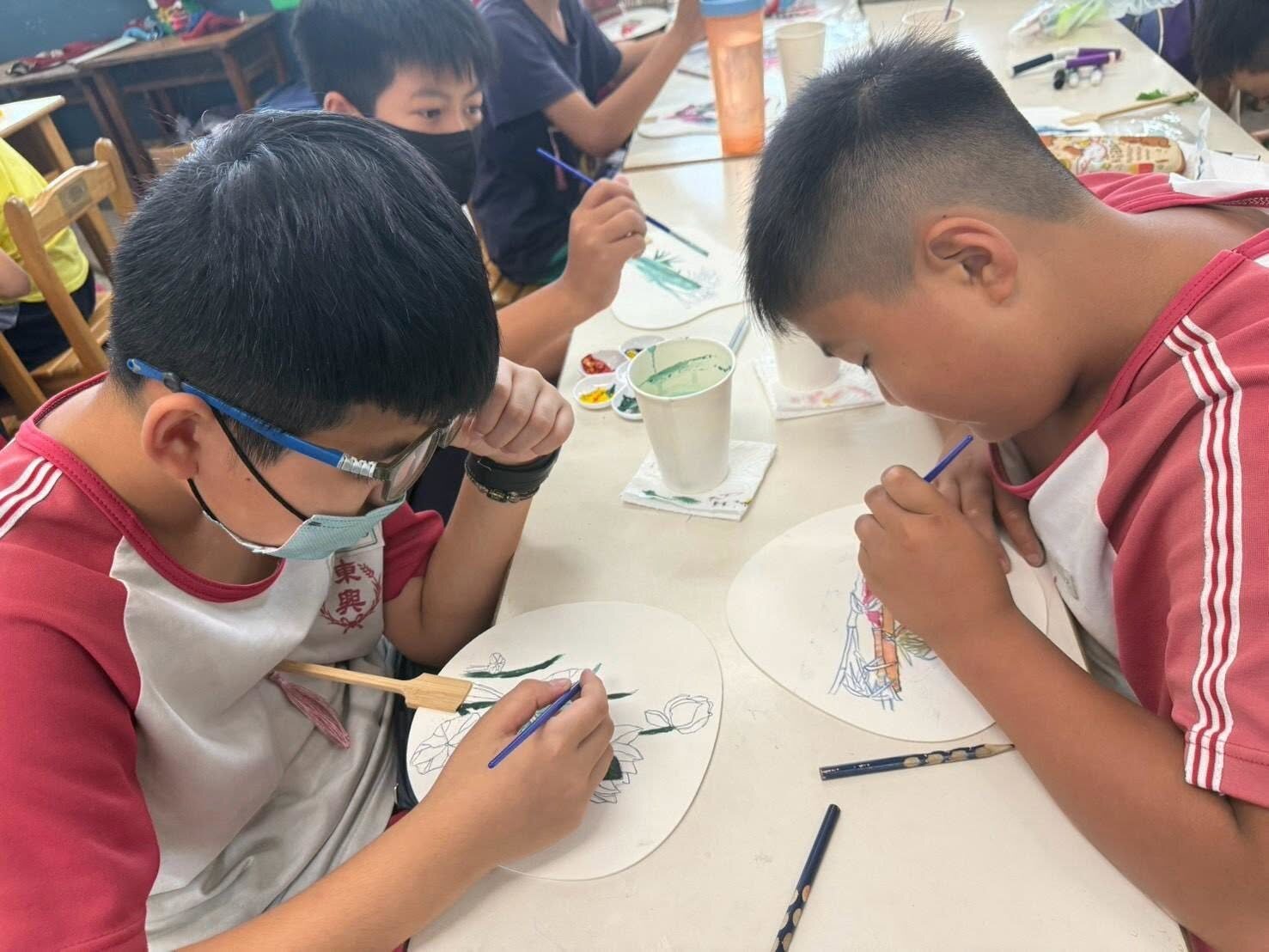 Dongshing students carefully painting fans during craft time