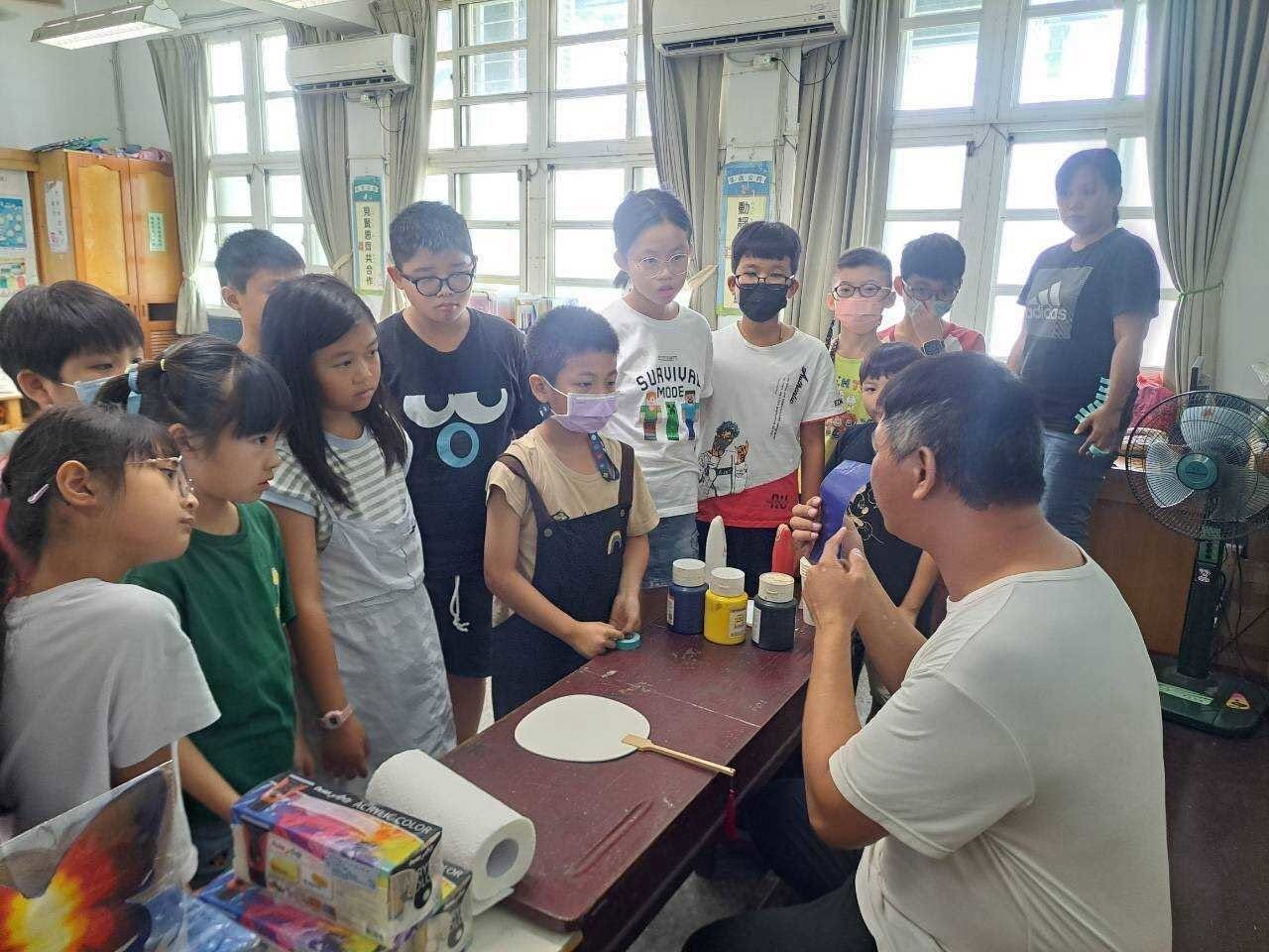 A craft teacher demonstrating fan painting to Dongshing students