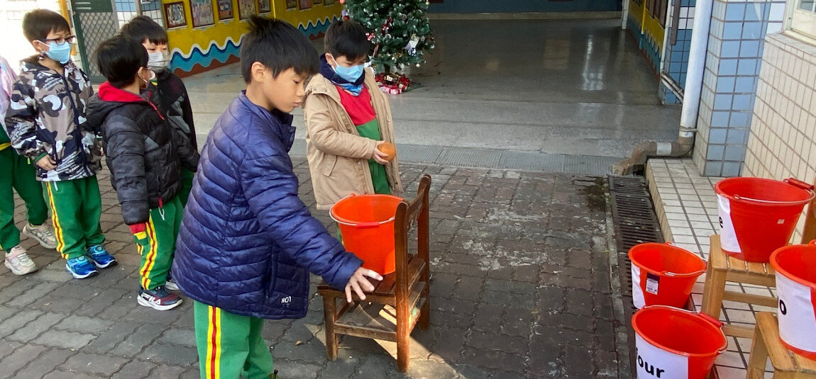 Students playing a bucket-toss game during the Christmas celebration