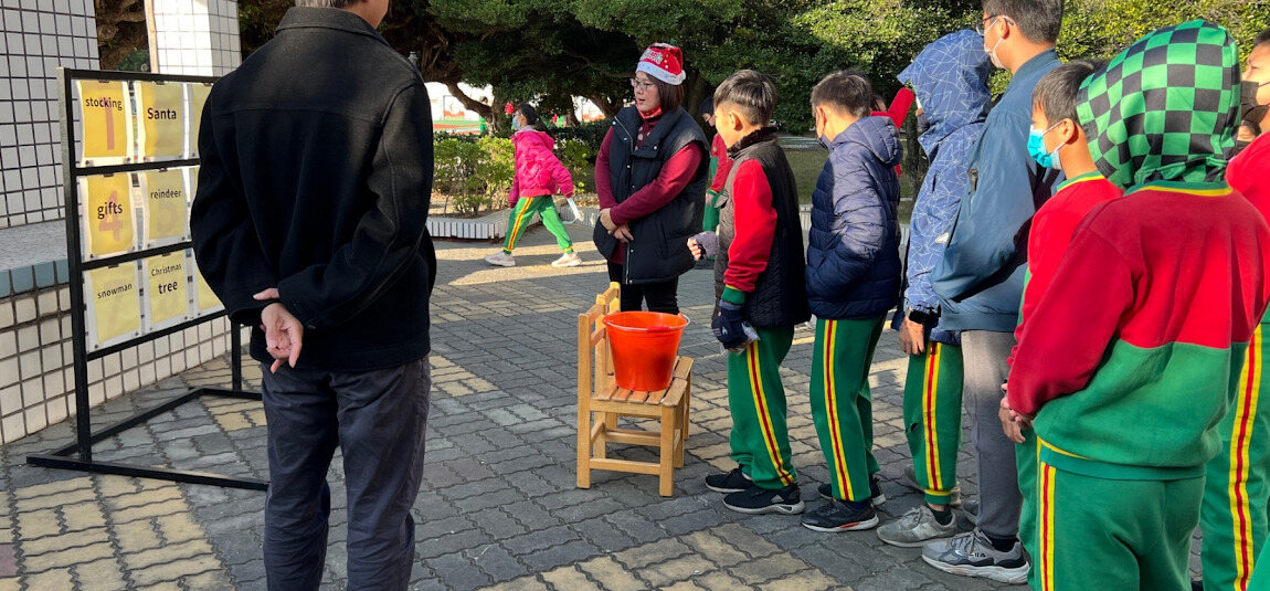 A teacher wearing a Santa hat as students line up for a game