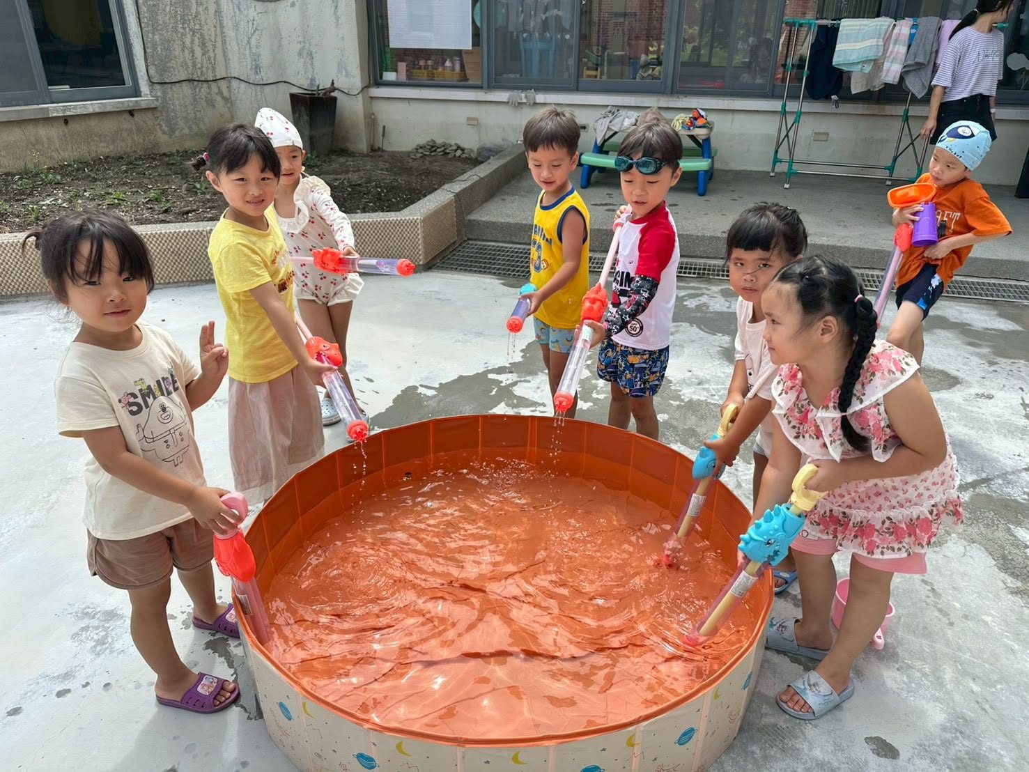 Kindergarten children playing with water guns