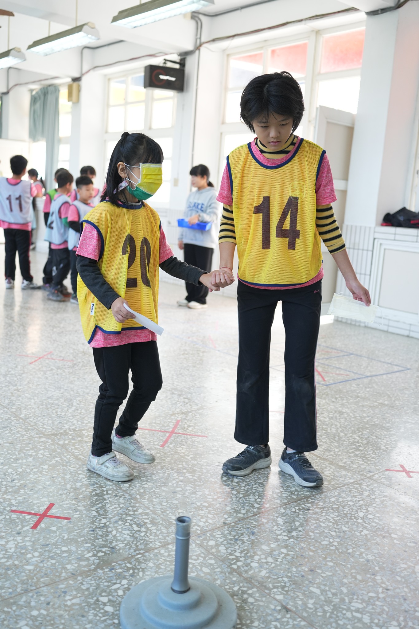 Older student holding hands with younger student at school anniversary relay