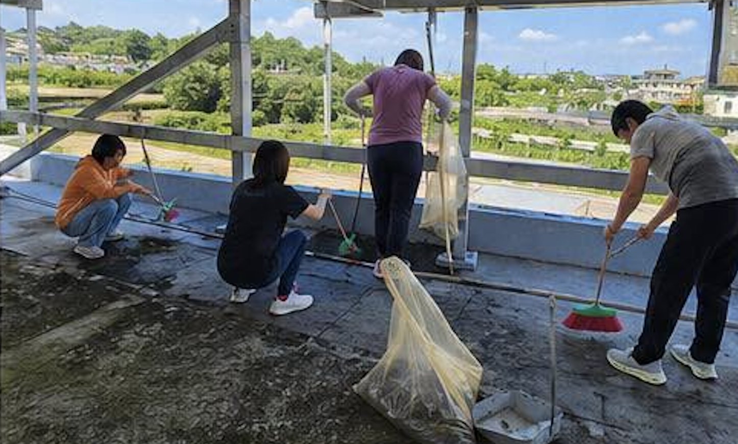 Fuchao Elementary staff clearing drains on the rooftop before the typhoon