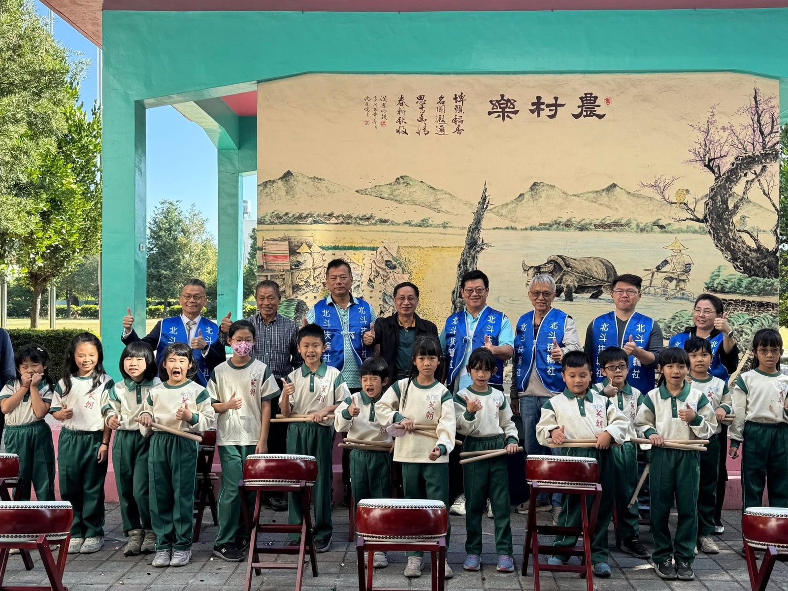 Fuchao Elementary drum troupe with community partners in front of the rural-life mural