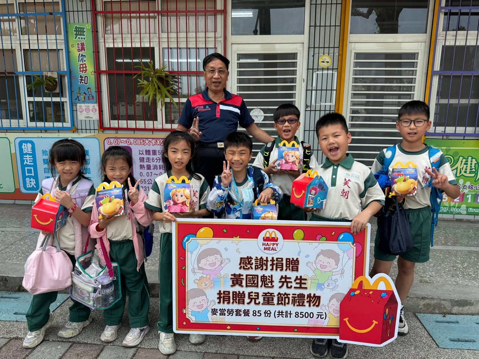 Principal Chou with students holding Children's Day gifts donated by Mr. Huang Guo-kui