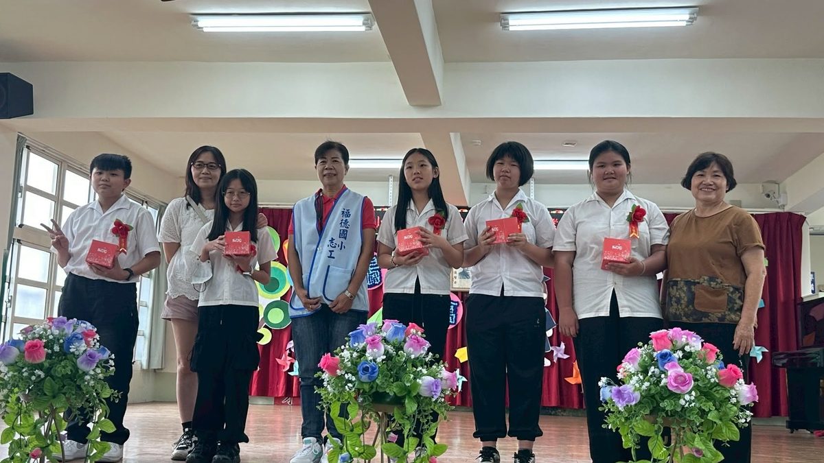Volunteers and graduates on stage holding graduation gifts