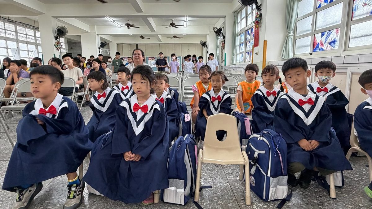 Kindergarten graduates in gowns seated and ready for rehearsal