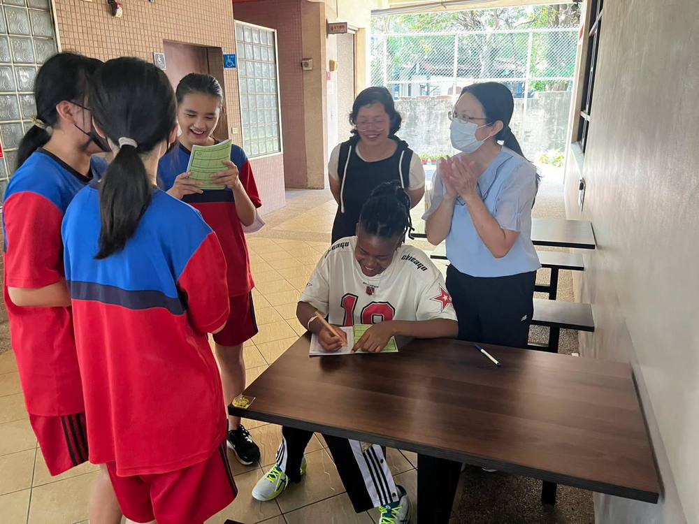 A teacher claps as students read from their booklets to Teacher Z