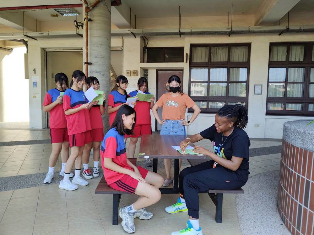 A line of students holding vocabulary booklets waits to talk with Teacher Z