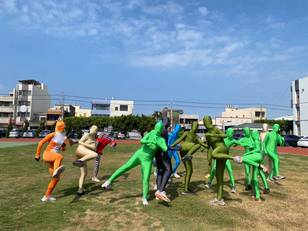 Bodysuit-clad students move together across the grass of the school field