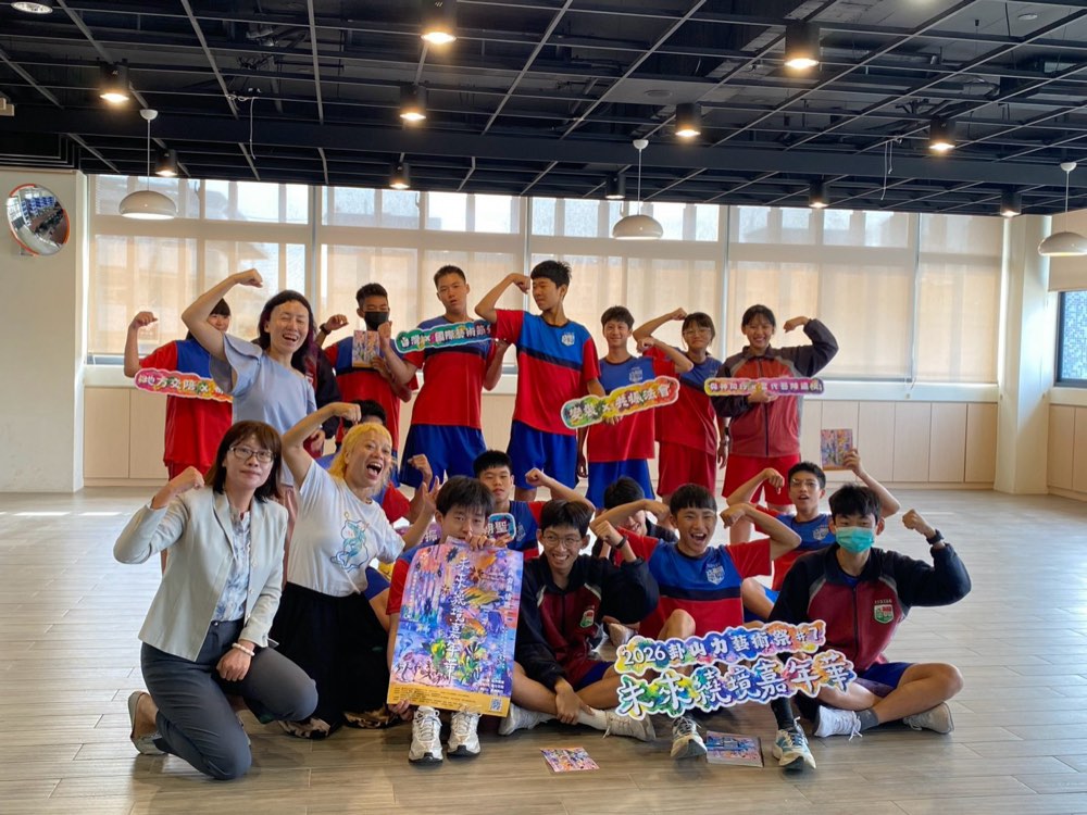 Students, teachers and the visiting artists flex for a group photo with the festival poster