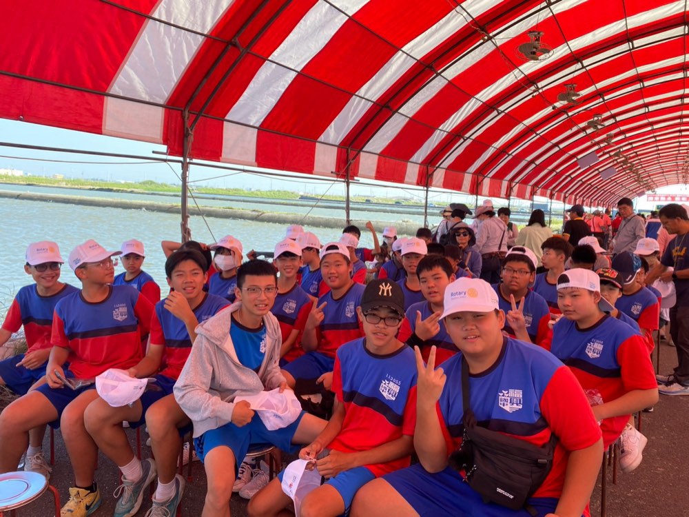 Fusing students seated under the red-and-white event tent before the cleanup